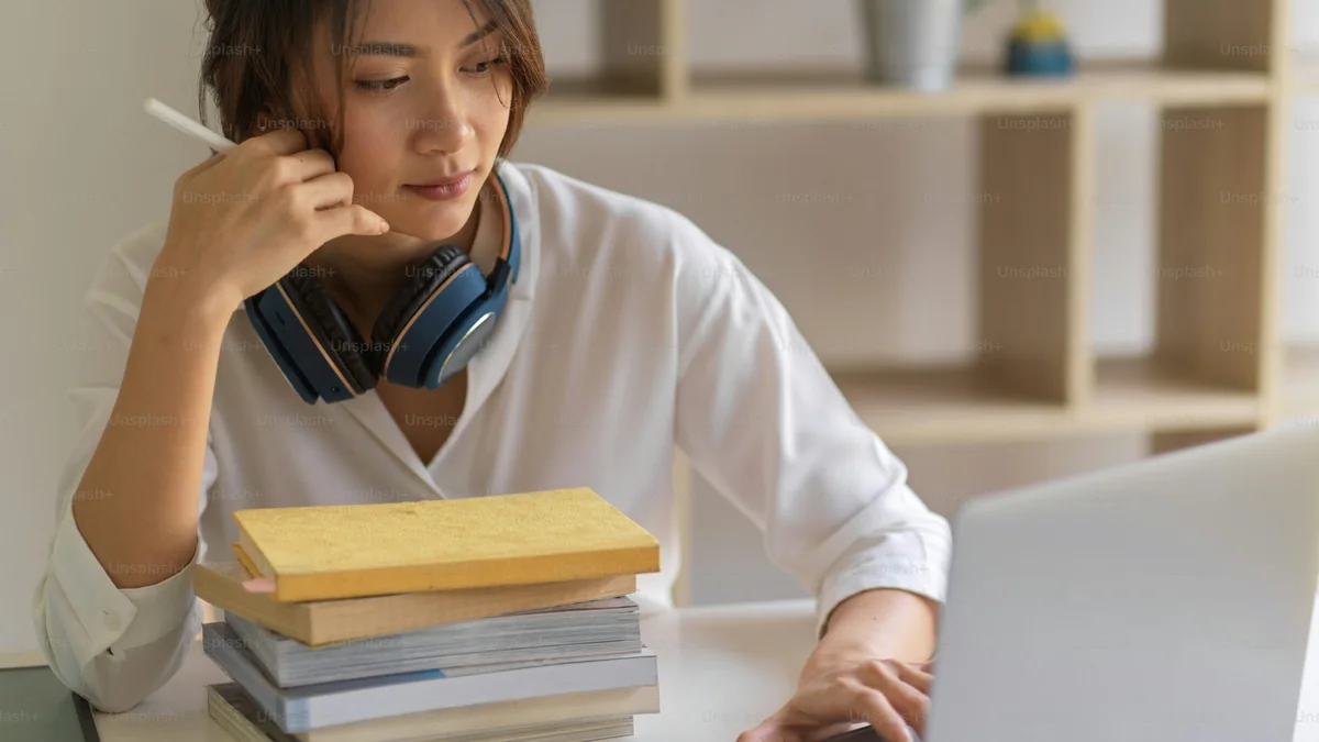 Apprenante étudiant avec ses livres et son ordinateur - illustration de l'article Comment trouver ses premiers clients en tant que thérapeute holistique (guide complet)